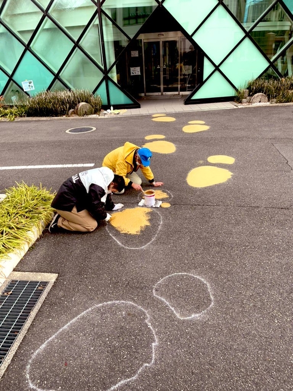 路面にペイントする石垣館長（右）と生物地球学科３年の岩本侑己さん＝12月24日