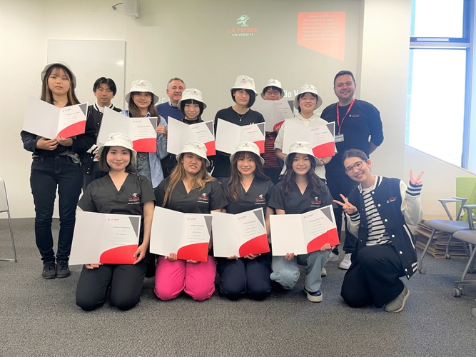 プレゼントしていただい帽子と修了証を持った学生達とスタッフ