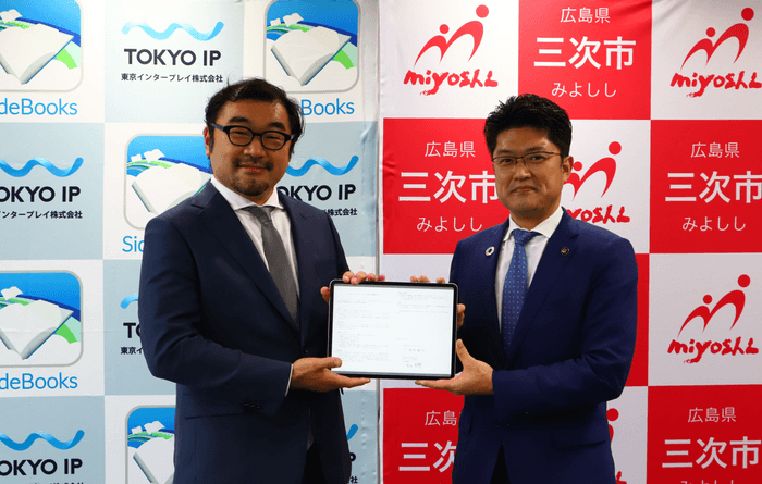 協定書(タブレット端末)を掲げる 三次市 福岡 誠志 市長(右)と東京IP 代表取締役 米田 英輝 