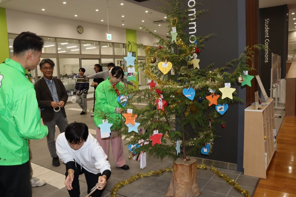 子どもたちの願いが書かれた短冊を1枚ずつ飾り付ける学生たち