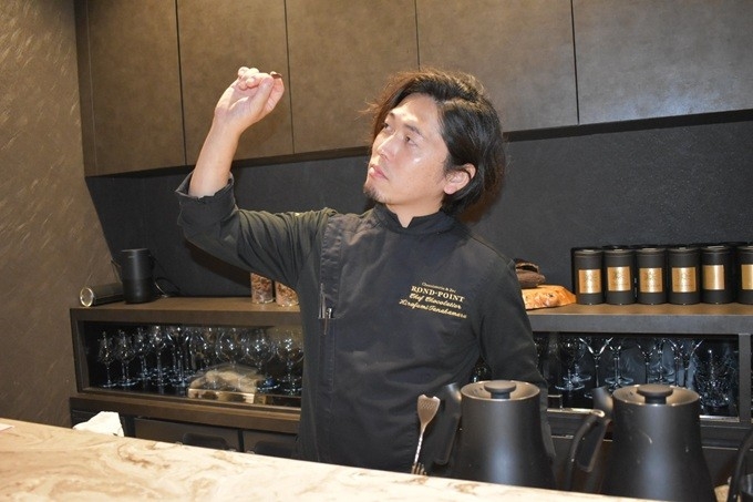 『柿の種のツヤを確認する田中丸 氏』