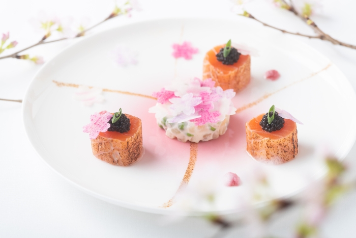 「MENU SAKURA」より前菜の「炙りスモークサーモンとキャビア 根セロリとグリンピース 桜舞うコポーとコンディモン」