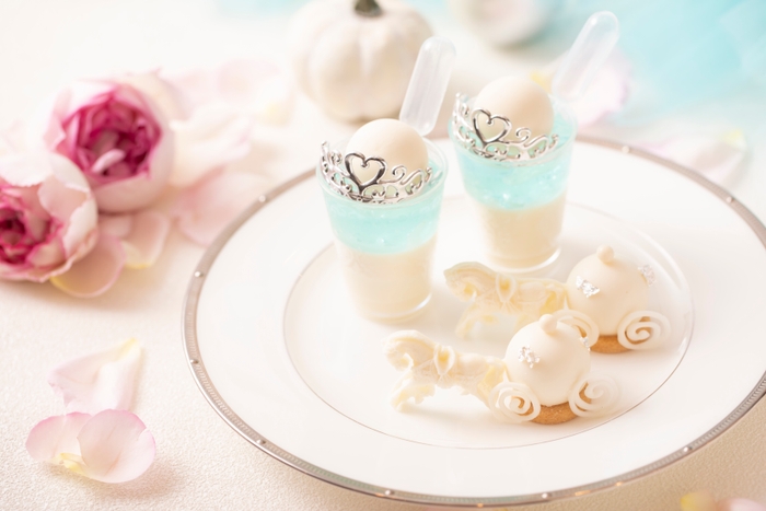 スタンド上段スイーツ イメージ:プリンセス・シンデレラパフェ~クリームソーダ風~は、魔法にかけられる瞬間のシンデレラを、キラキラと光り輝く泡が美しい“ソーダ”で演出。馬車ムースは、ノンアルコールカクテルの“シンデレラ”をムースで表現。パインやオレンジなどを使いトロピカルな味わいに仕立てました。