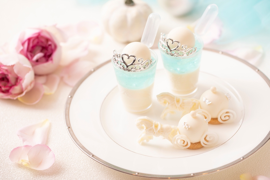 スタンド上段スイーツ イメージ:プリンセス・シンデレラパフェ~クリームソーダ風~は、魔法にかけられる瞬間のシンデレラを、キラキラと光り輝く泡が美しい“ソーダ”で演出。馬車ムースは、ノンアルコールカクテルの“シンデレラ”をムースで表現。パインやオレンジなどを使いトロピカルな味わいに仕立てました。