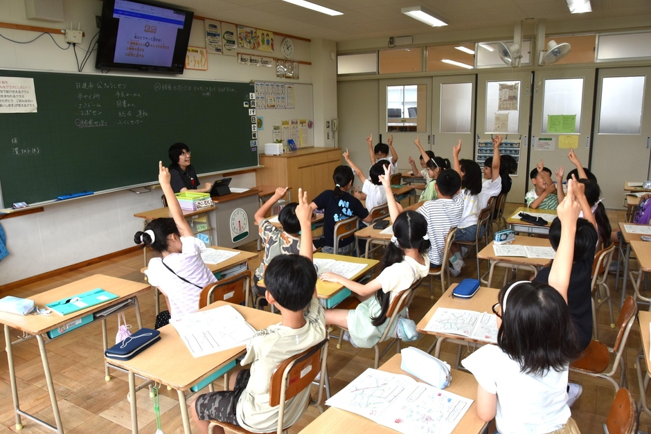 クイズで正解だと思う番号に元気よく手を挙げる児童たち
