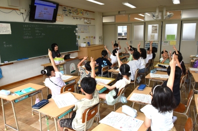 クイズで正解だと思う番号に元気よく手を挙げる児童たち