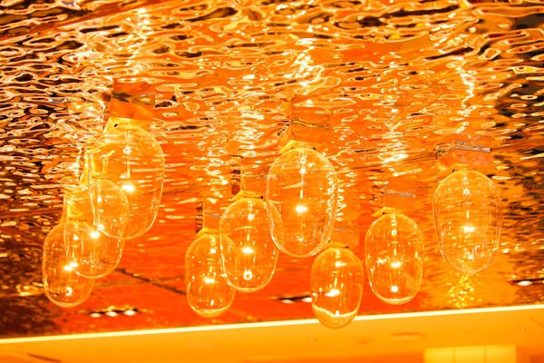 「廻転鮨 銀座おのでら本店」内装／波、イカ釣り舟の明かりを彷彿とさせる天井、夕陽をイメージした橙色の壁