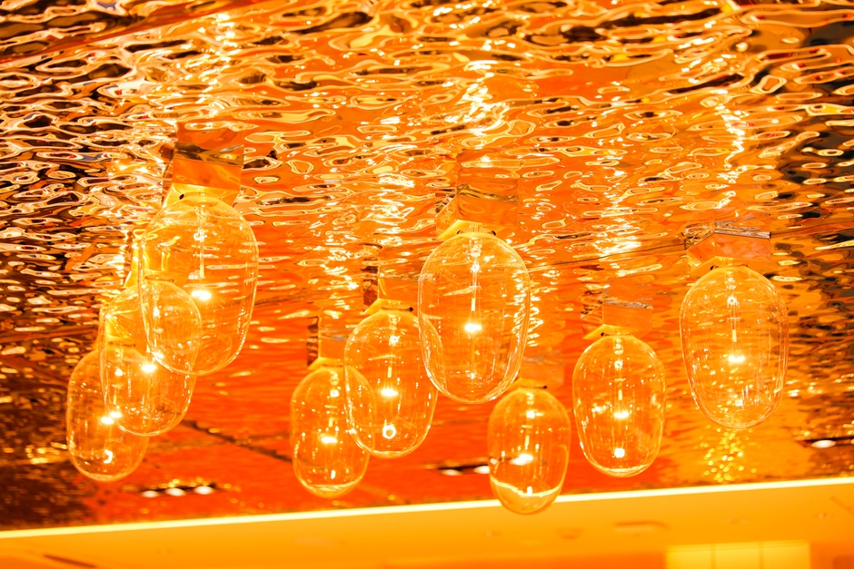 「廻転鮨 銀座おのでら本店」内装／波、イカ釣り舟の明かりを彷彿とさせる天井、夕陽をイメージした橙色の壁