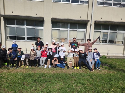 学校に届いたベンチに座りながら,製作者の方と記念写真。