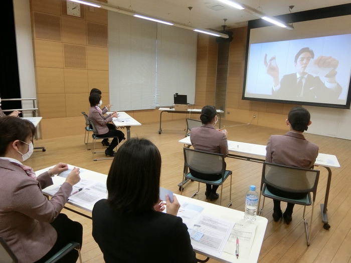 スクリーンに講師を映し出し、実践的なサービスのコツを伝授