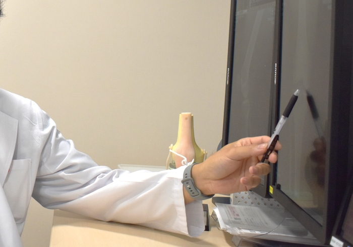 骨の状態を確認しながら、継続的な評価の必要性について説明する診療場面（イメージ）