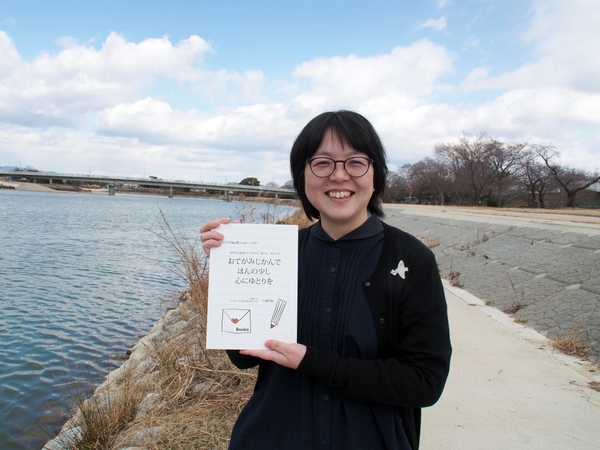 自著『おてがみじかんで　ほんの少し　心にゆとりを』を手にする著者