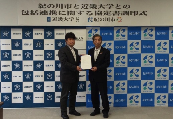 調印式にて書面を交わす中村愼司紀の川市長(右)と近畿大学生物理工学部・松本和也学部長(左)