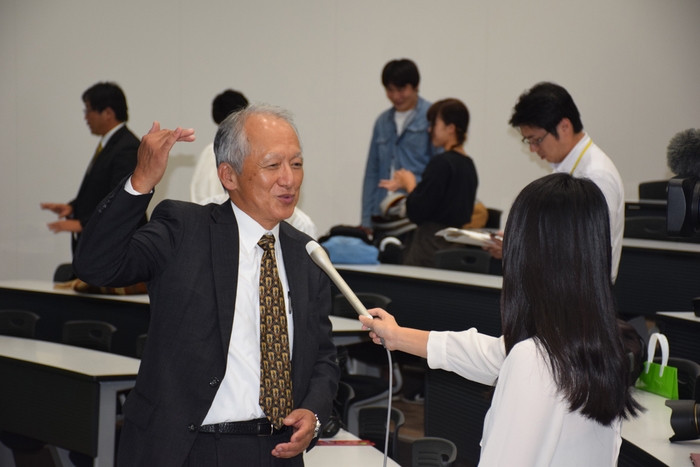 記者の取材を受ける石垣教授