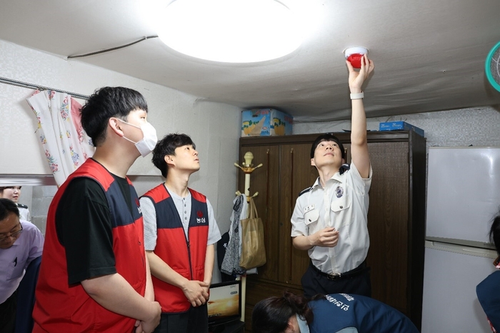 キャンペーンで配布された火災報知器を取り付ける農心社員と消防庁職員