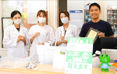 カウンターで薬剤師のスタッフと。生まれ育った足立区からオンライン薬局の普及を進めていく決意