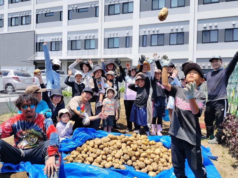 こうのすえんの収穫の様子。医療法人社団鴻愛会「こうのす共生病院」の畑ベースのコミュニティ「こうのすえん」で、地域住民と職員が協力して野菜を収穫する様子。地域共生とウェルビーイングを実践する現場の風景です。