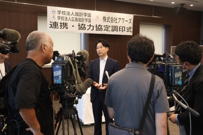 マスコミの囲み取材に答える山本社長（中央）