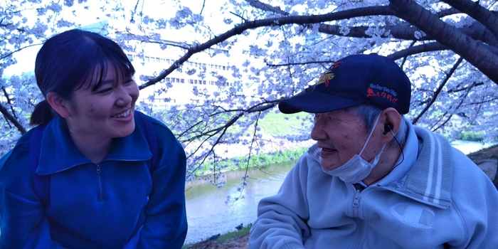 桜の木の下で学生と歓談する施設利用者さん