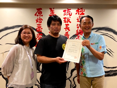 助成証書の授与(沖縄県で実施) プログラムB助成団体代表の泉崎子ども食堂ちねんや~代表者(写真左・中)と キユーピー那覇営業所長(写真右)