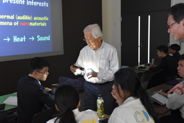 カーボンナノチューブに白色LEDの光を当て実演する飯島終身教授