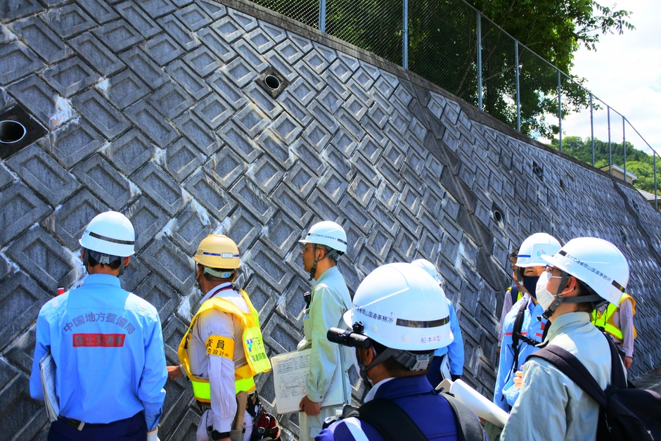 国道わきの斜面を点検する佐藤教授や国交省職員ら=岡山県建部町で