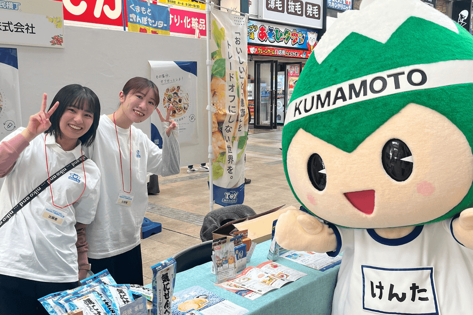トイメディカル株式会社スタッフ（左）と健やか生活習慣くまもと県民運動キャラクター  「ASO坊健太くん」（右）