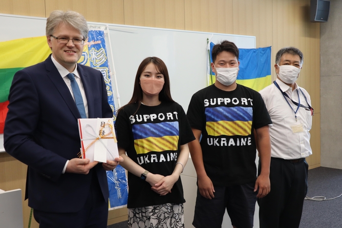 (左から)ジーカス大使、目録を手渡した安藤桃花さんと山田拓斗さん、稲葉教授