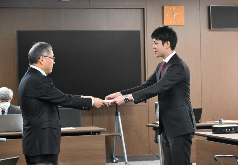 野口学長から採択通知を授与される黒川助教