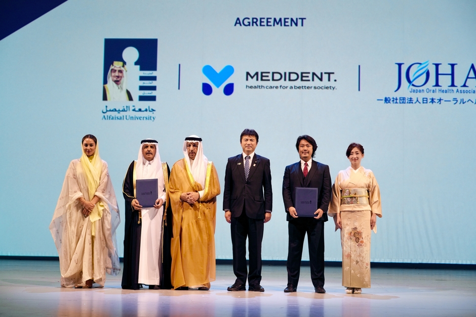 「大阪・関西万博『日・サウジEXPO投資フォーラム』壇上での調印。左から:アルファイサル大学・ヌール・A・アル・サアドゥーンセンター長、アルファイサル大学ムハンマド・Ali・アル・ハイアザ学長、サウジアラビア王国ハーリド・アル=ファーレフ投資大臣、古賀友一郎経済産業副大臣、メディデント代表 富田大介、一般社団法人日本オーラルヘルス協会富田由美子理事」