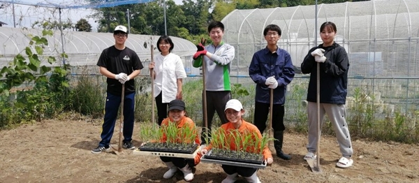 近畿大学農学部の実験圃場での実習の様子。近畿大学農学部の学生（後列）と桂高等学校の生徒（前列）