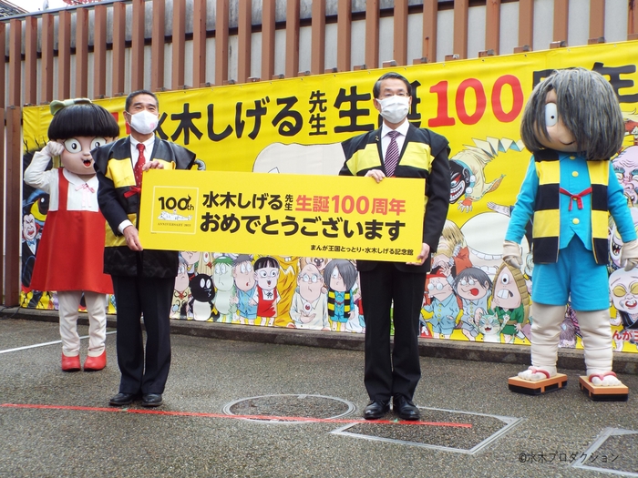 「水木しげる生誕100周年お祝いペストリー」お披露目式の様子(左から、ねこ娘、境港市長 伊達憲太郎、鳥取県知事 平井伸治、ゲゲゲの鬼太郎)