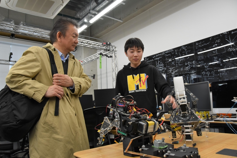 池本研究室でロボットを手に説明する学生