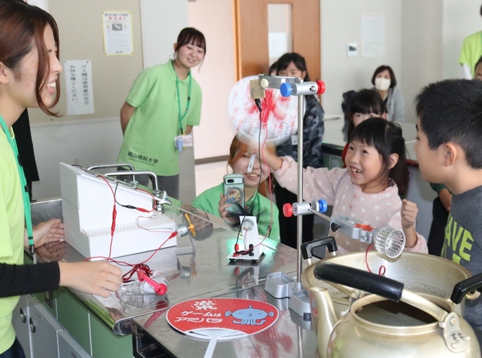 うちわで風を送って発電に挑戦する参加者