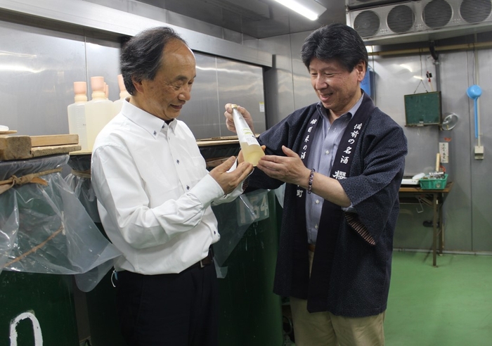 サクラ酵母で仕込んだタンクの前で出来具合を見る滝澤教授(左)と花房社長(右)