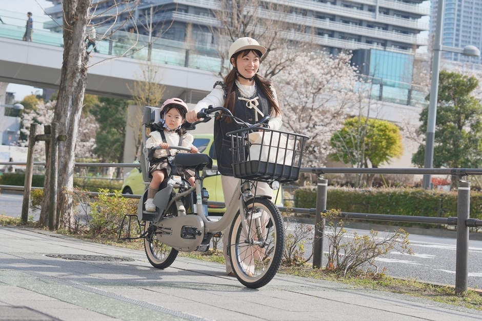 子ども乗せ自転車を押して歩道を歩くママ