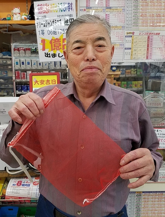 お店の前で網(ネット)を持つ店主