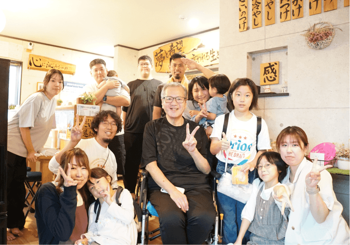 今回の外出に参加したご本人、ご家族、リハビリ職員、店主ら。地域とのつながりから実現した、念願の「いこい」でのひととき。