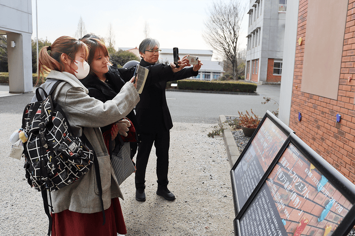 壁面に向けてスマホをかざし、AR体験を楽しむ学生たち。後方が白砂さん