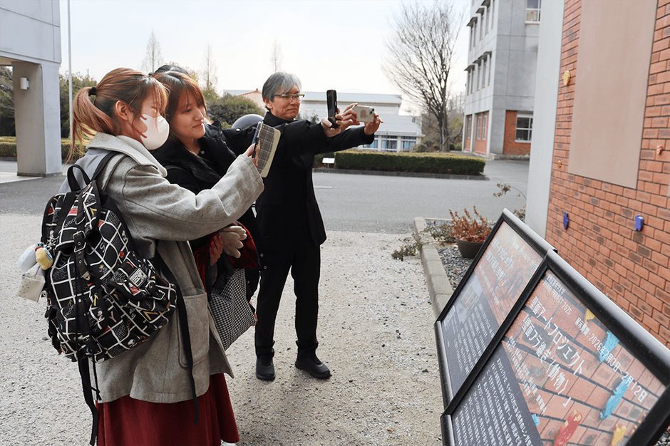 壁面に向けてスマホをかざし、AR体験を楽しむ学生たち。後方が白砂さん