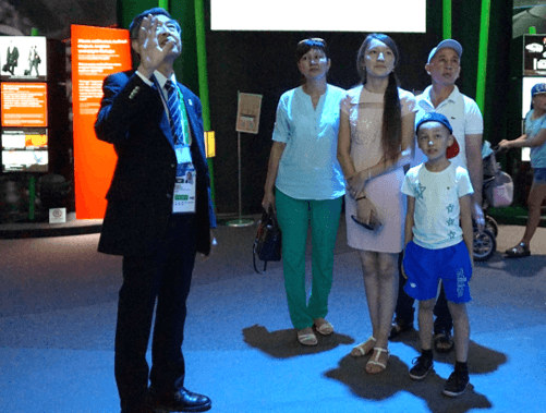 日本館を観覧するアマンガラエフさん一家(右)と芝元・日本館館長(左)