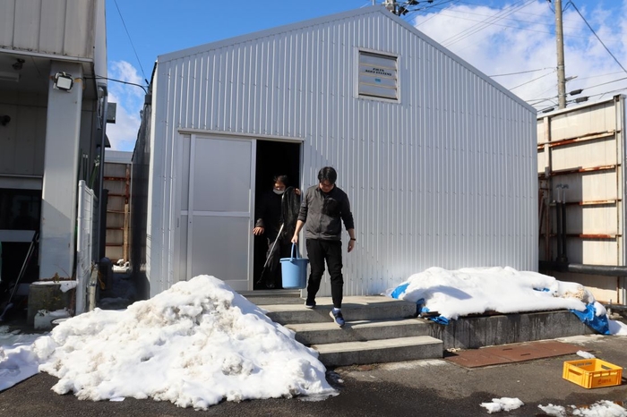 周囲に雪が残る養殖場の外観