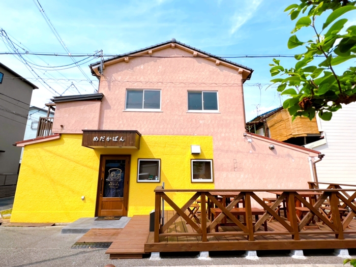 めだかぱんのイメージカラーの黄色とウッドデッキで存在感のある外観