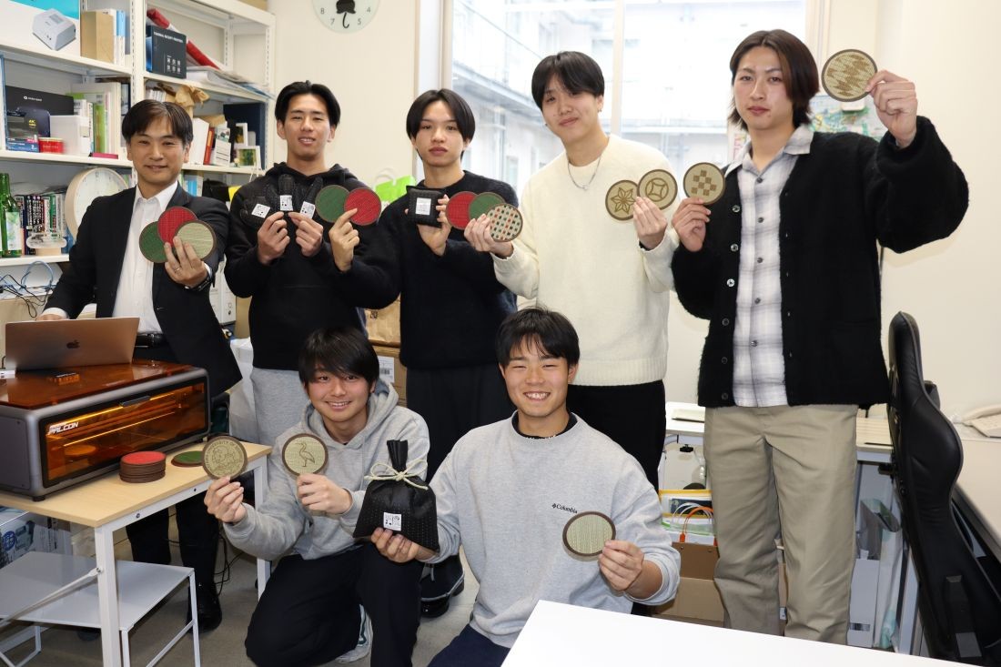 イグサの消臭袋やコースターを手にする(後列左から)指導教員の高橋良平准教授、松田魁斗さん、岡部翔隆さん、上根暖也さん、木村柊斗さん(前列左から)板谷匠晃さん、大西啓太さん