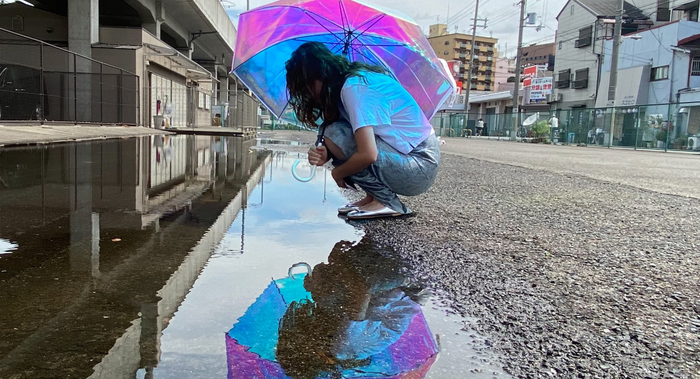 雨の日の暗い野外でも、傘のオーロラカラーが地面や水たまりに反射して映える写真が撮れることからオーロラビニール傘の自撮りが流行っている。