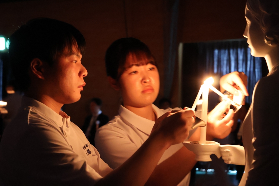ナイチンゲール像から灯を受け取る学生