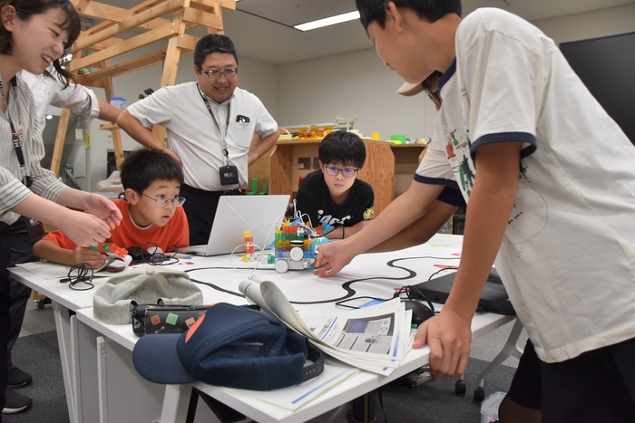 蛇行するコースでゴールできるかな?マシンの動きに注目する子供たち