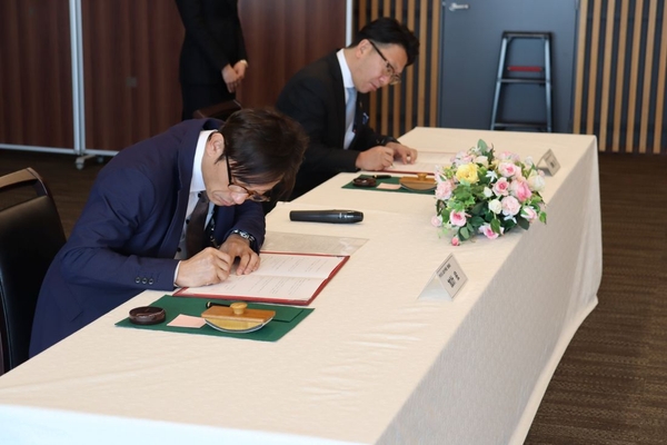 協定書に署名する（左から）加計理事長と尾崎会長