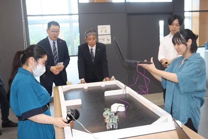 学生たちのロボット操作に見入る烏田社長と小林マネージャー