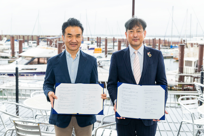 署名した包括連携協定書を持ち記念写真を撮る高橋此花区長（右）と松尾代表取締役（左）